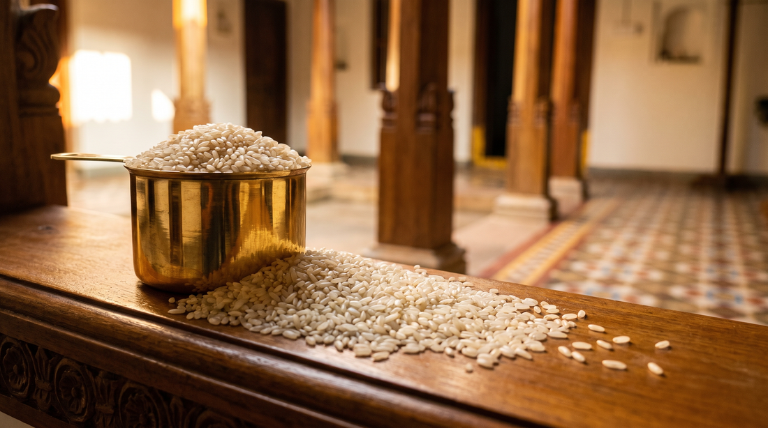 Raw seeraga samba rice heaped in a polished brass measure on carved teak, courtyard light