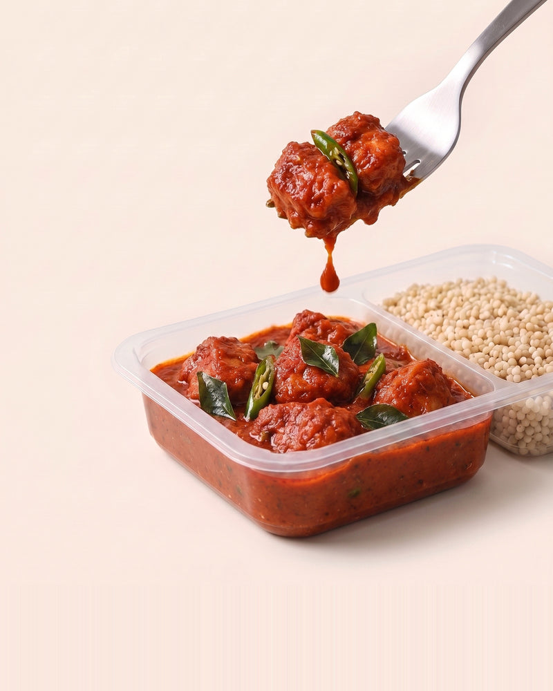 Andhra Chilli Chicken, a forkful lifted from the open tray, chicken in Andhra chilli gravy beside pearl millet