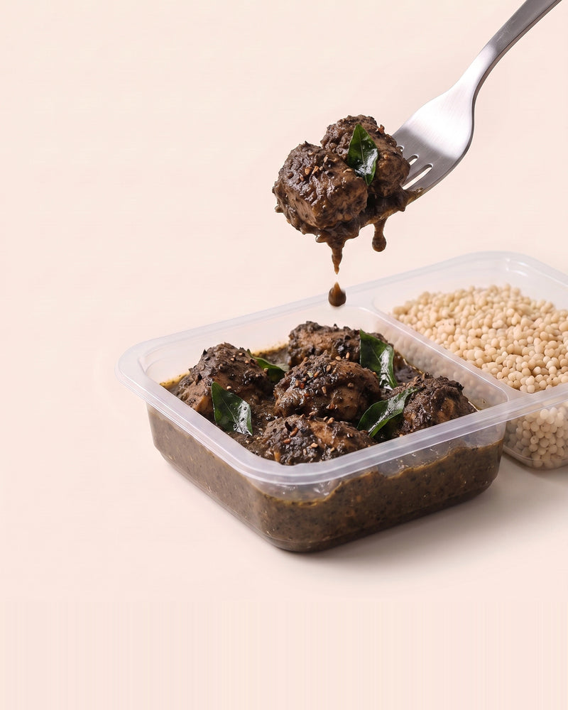 Chettinad Pepper Chicken, a forkful lifted from the open tray, black pepper masala beside pearl millet