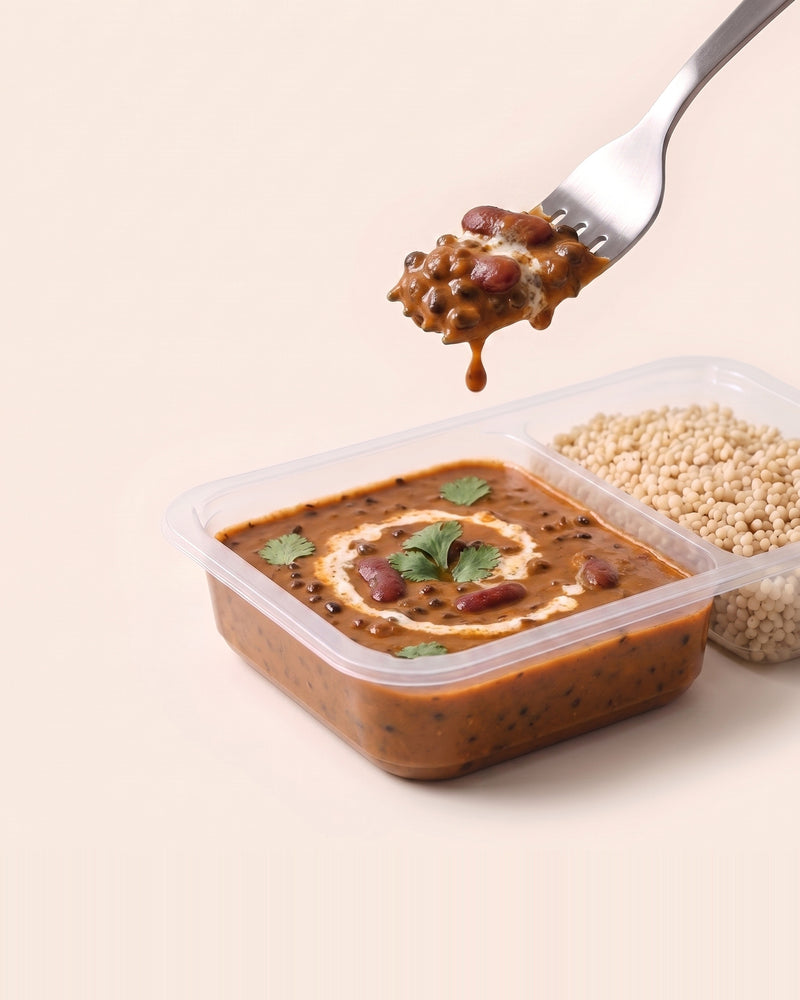 Dal Makhani Protein Bowl, a forkful lifted from the open tray, dal beside pearl millet
