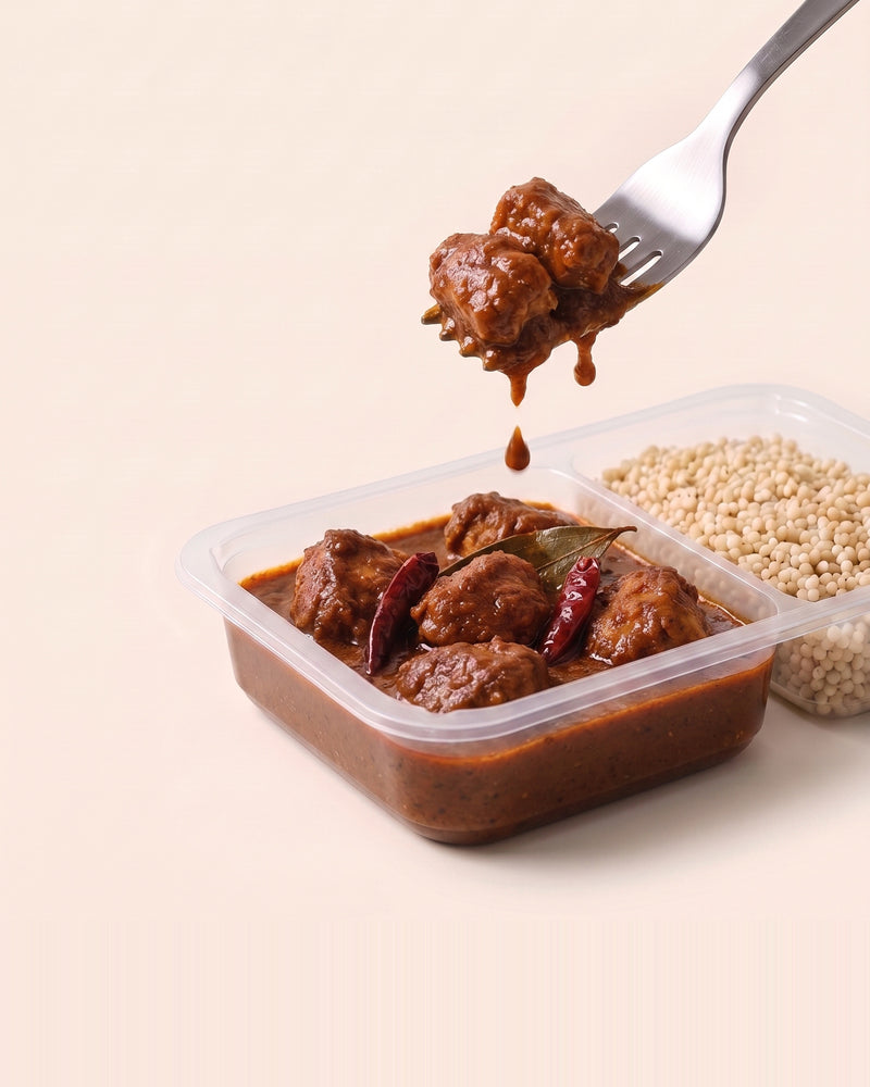 Goan Vindaloo Chicken Bowl, a forkful lifted from the open tray, vindaloo beside pearl millet