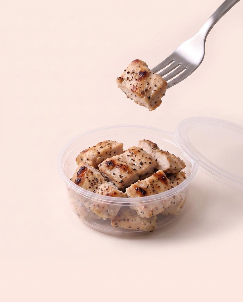 Grilled Chicken High Protein Top-up in its tub, a forkful lifted, ready to eat